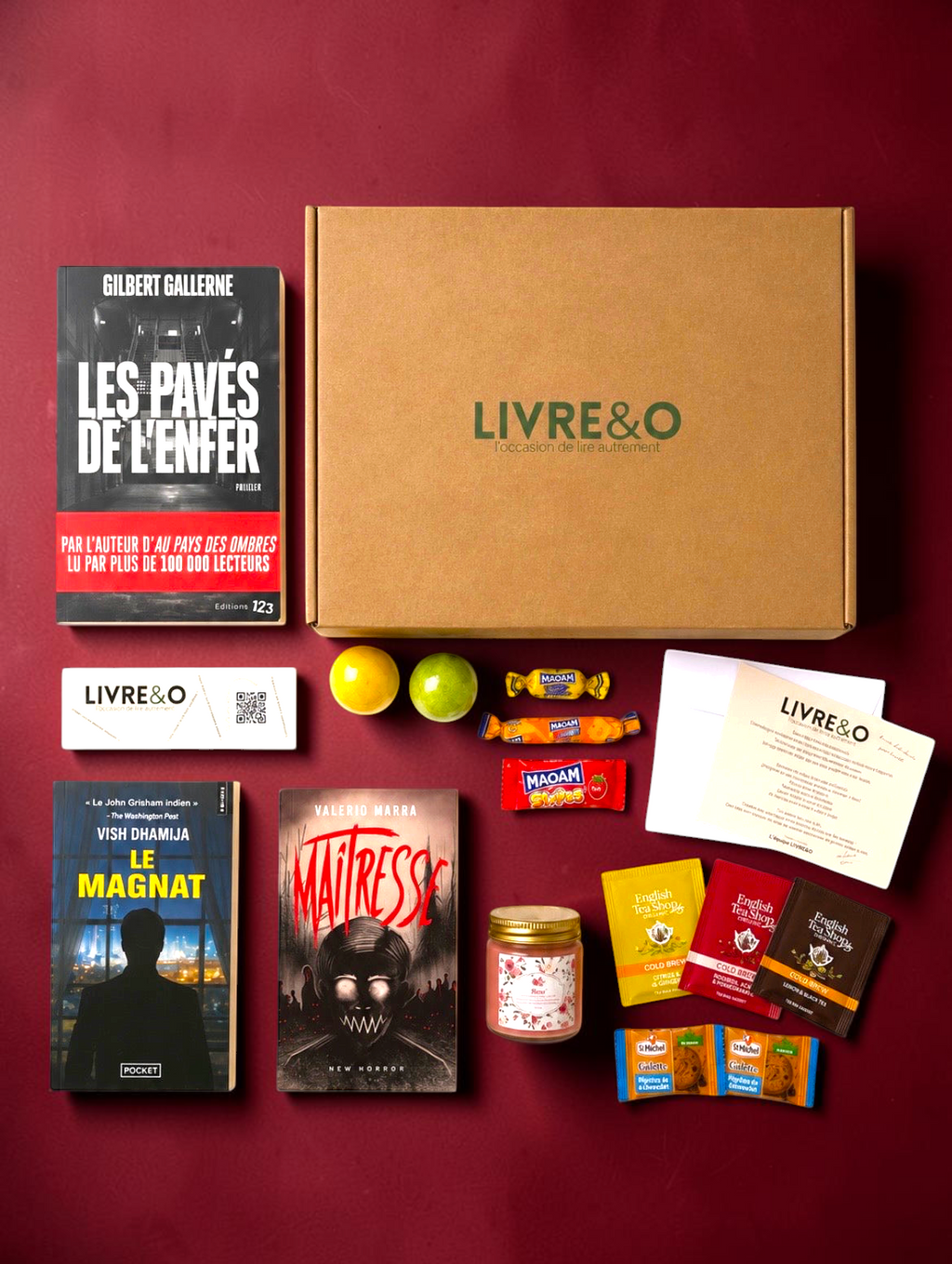 Box sélection LIVRE&O contenant trois romans noirs, des sachets de thé, des gourmandises et une bougie sur fond noir