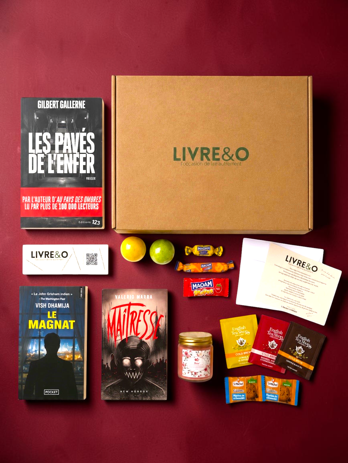 Box sélection LIVRE&O contenant trois romans noirs, des sachets de thé, des gourmandises et une bougie sur fond noir