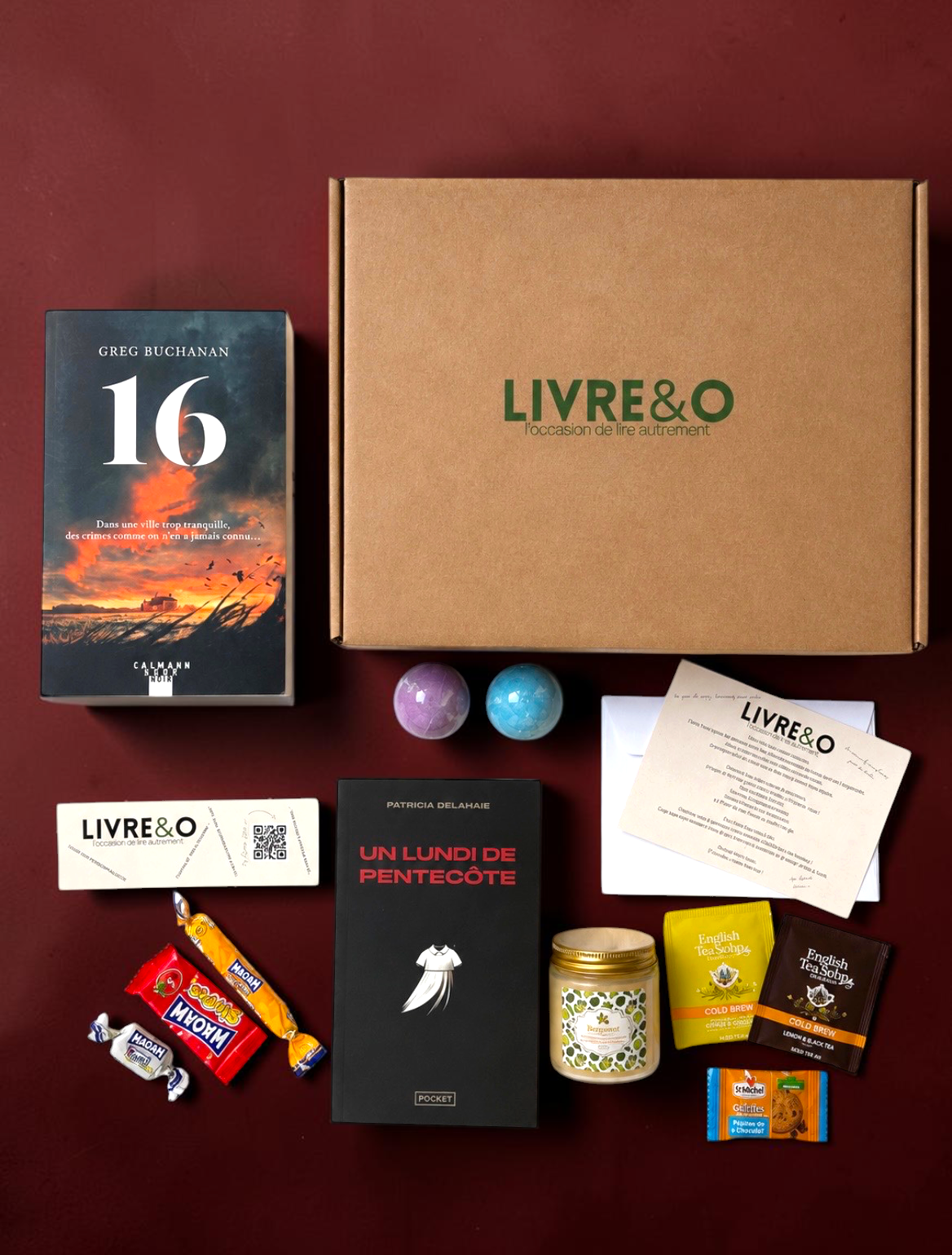 Box découverte LIVRE&O contenant deux romans noirs, des gourmandises, du thé et des surprises sur fond bordeaux.