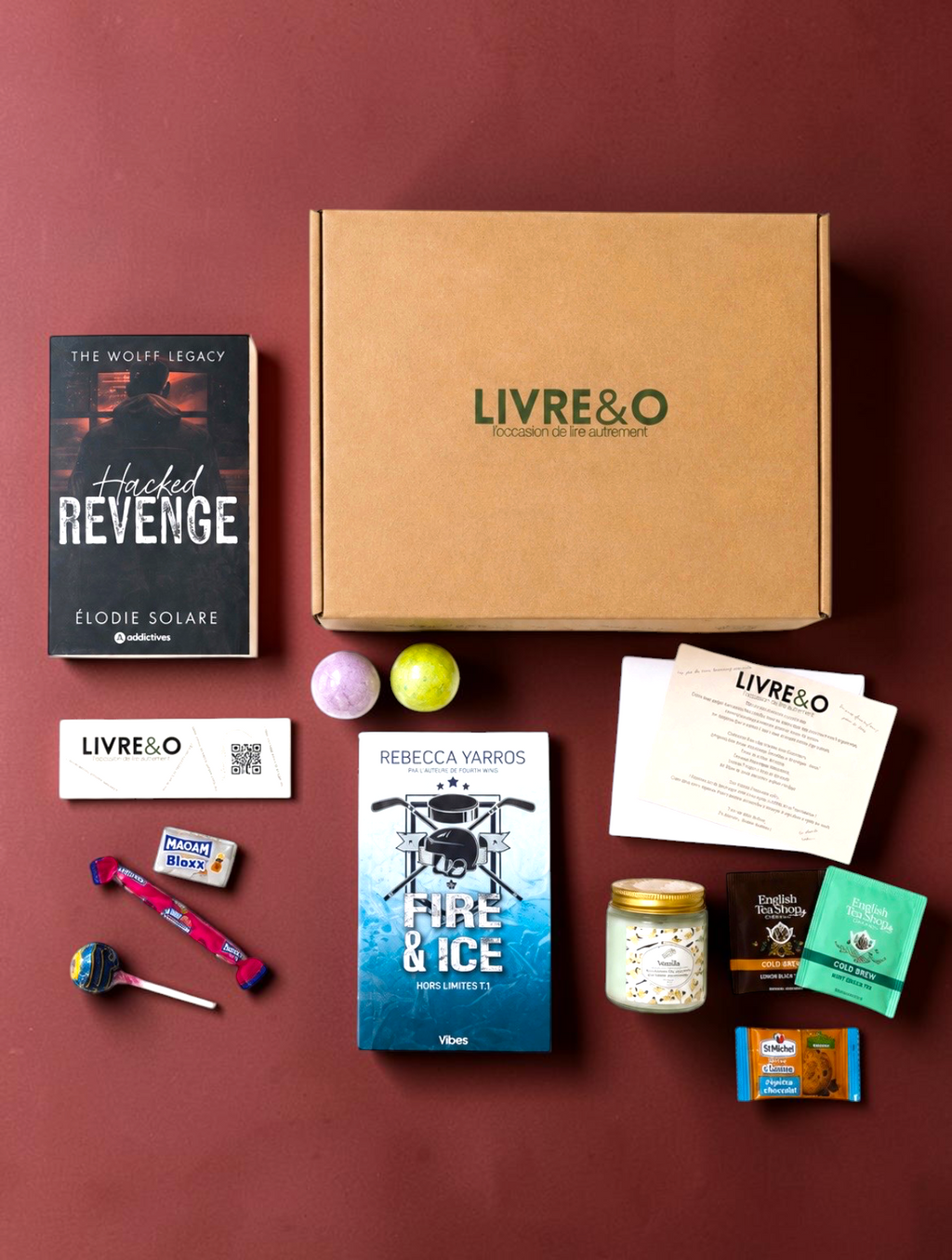Box découverte Romance LIVRE&O contenant des romans, une bougie, des thés et des gourmandises sur fond bordeaux