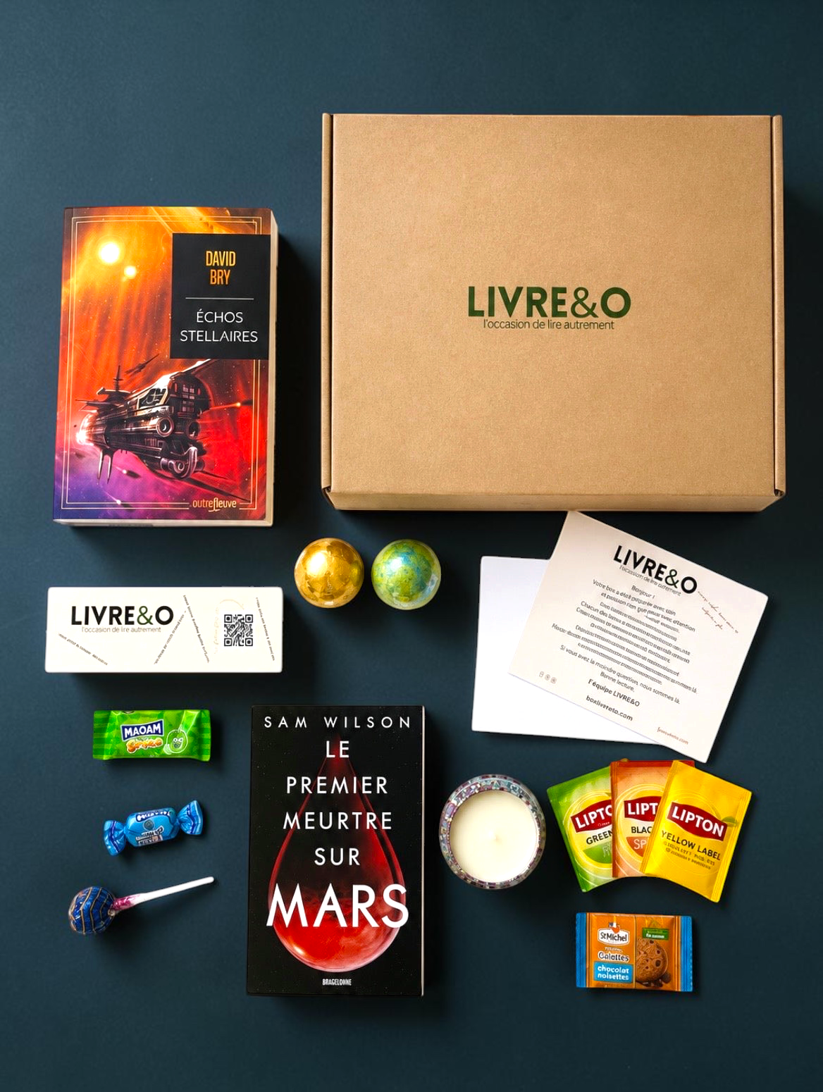 Box découverte science-fiction LIVRE&O contenant deux romans, des thés, des gourmandises et une bougie sur fond sombre