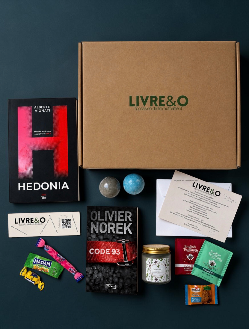 Box découverte LIVRE&O contenant deux romans thriller, des sachets de thé, des bonbons et une bougie parfumée.