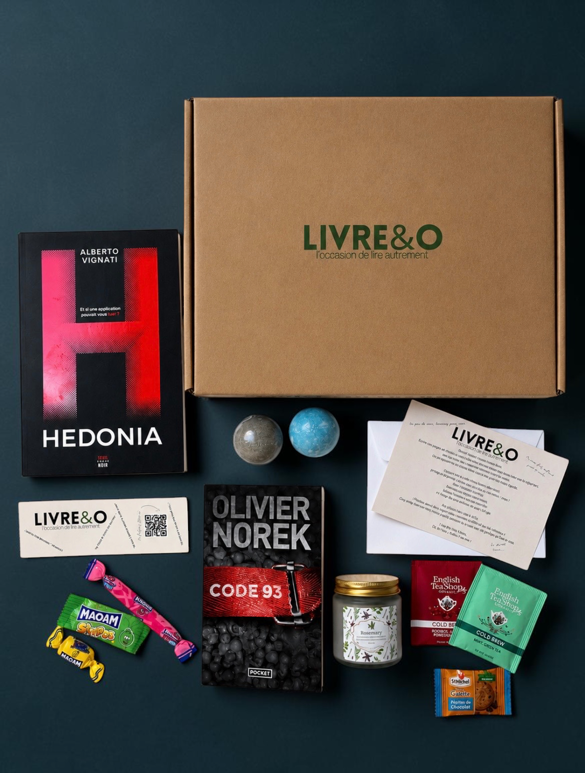 Box découverte LIVRE&O contenant deux romans thriller, des sachets de thé, des bonbons et une bougie parfumée.