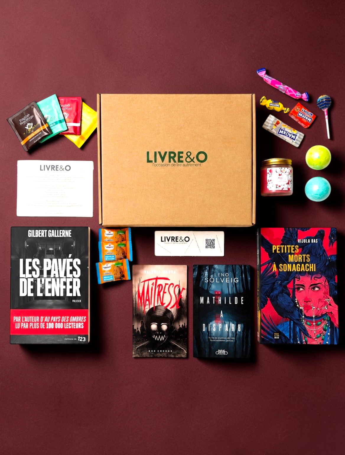 Box LIVRE&O contenant quatre romans de suspense, des gourmandises et des surprises sur un fond blanc