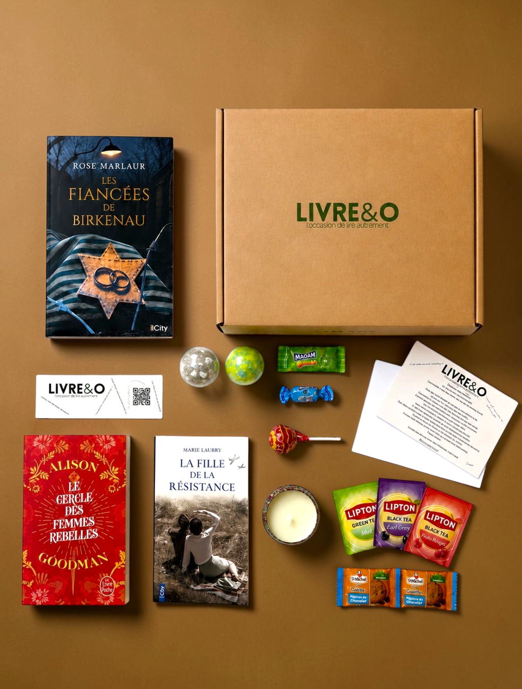 Box LIVRE&O contenant trois romans historiques, des sachets de thé, des gourmandises et une bougie sur fond marron