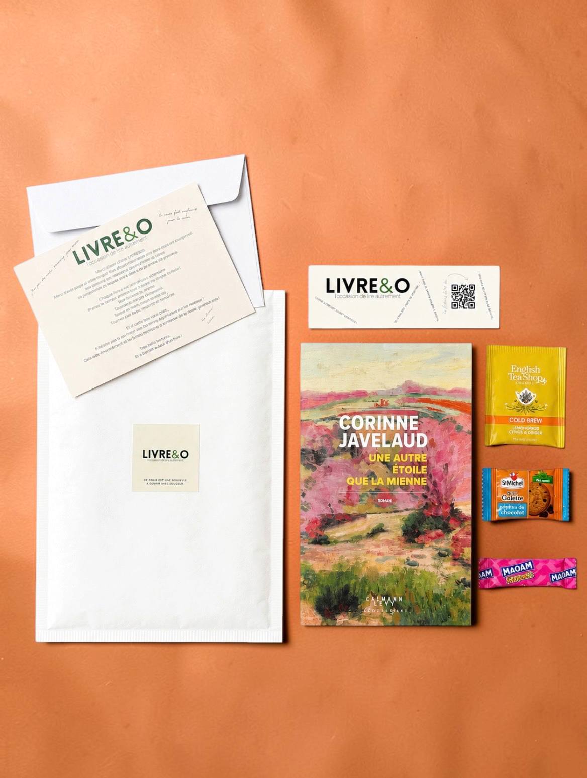 Enveloppe LIVRE&O contenant un roman contemporain, un marque-page, du thé et des gourmandises sur fond orange