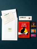 Enveloppe LIVRE&O contenant un roman thriller, un marque-page, du thé et des gourmandises sur fond sombre.
