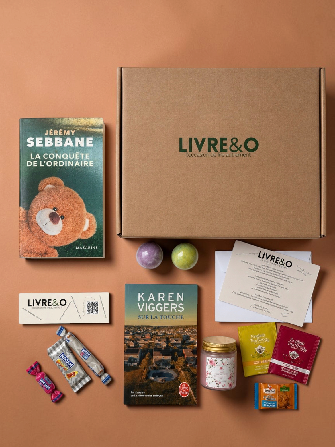 Box découverte LIVRE&O contenant deux romans contemporains, des gourmandises, du thé et des surprises sur fond beige