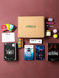 Box LIVRE&O Romance contenant quatre romans d'occasion, des sachets de thé, des friandises et une bougie parfumée.